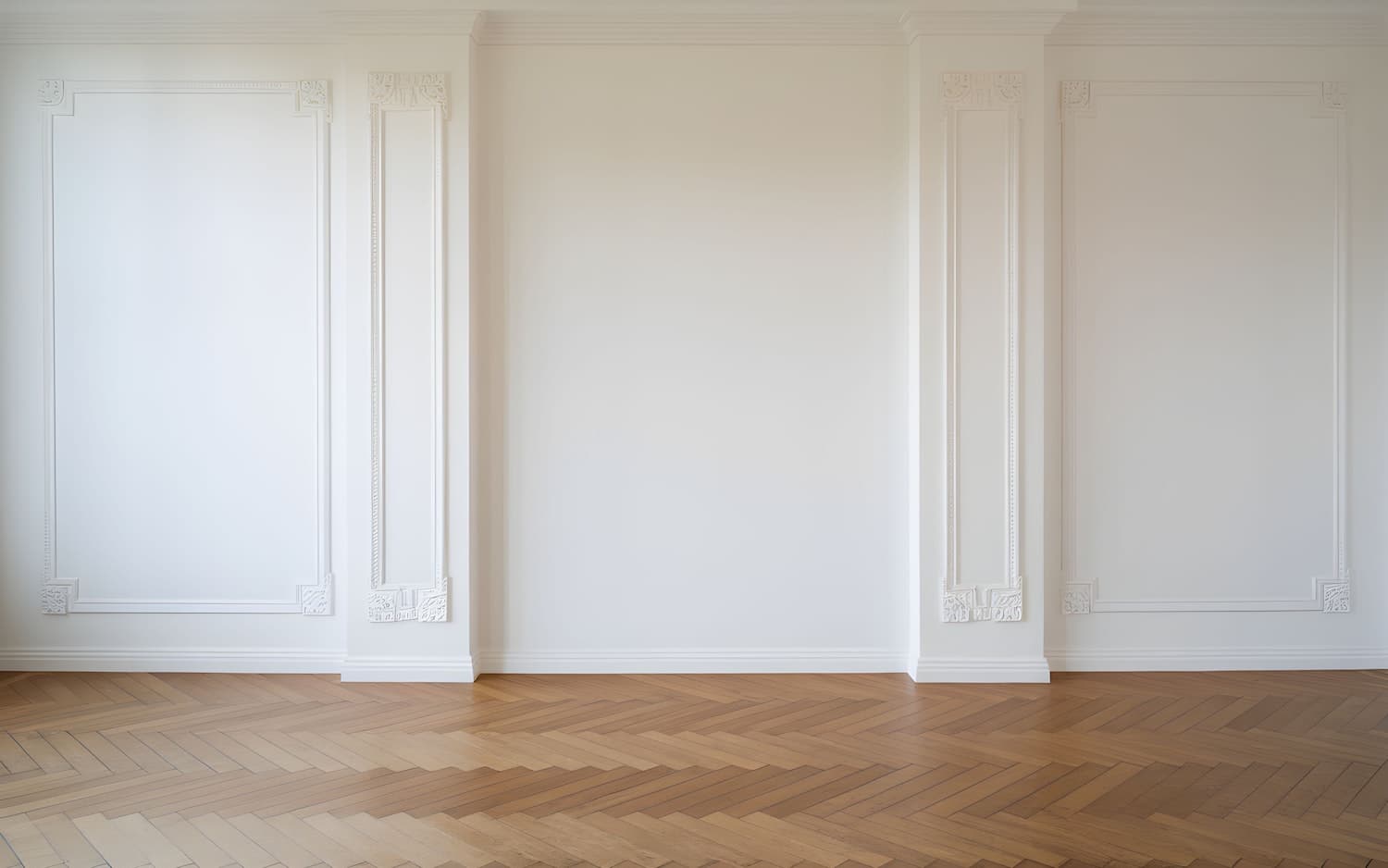 Bright interior with herringbone hardwood flooring and detailed wall molding